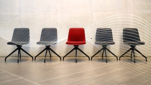 row of gray chairs with one red chair